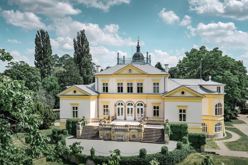 une grande maison jaune avec une tourelle dans l'établissement Zámek Dobřenice, 