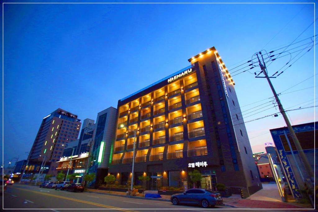 Gwangyang的住宿－Hotel Haemaru，城市街道上的一座建筑,前面有停车位