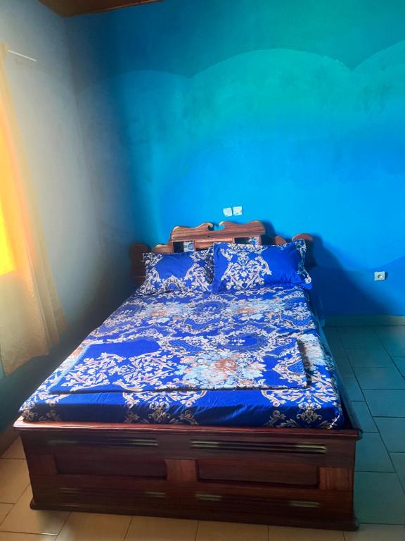 A&G Guest House Kumba في Kumba: سرير في غرفة ذات جدار ازرق