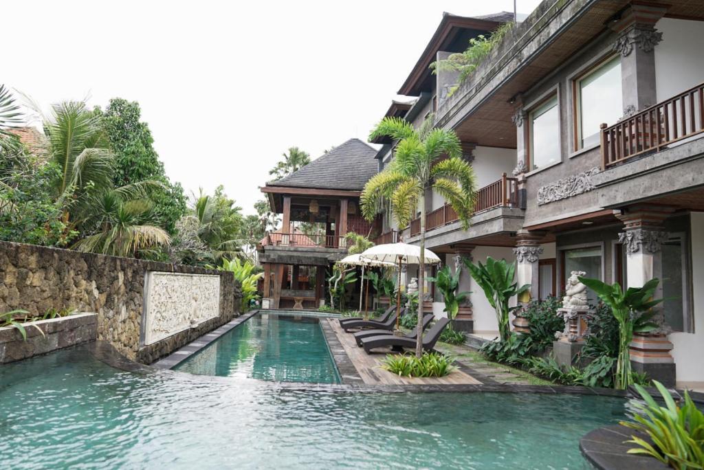 a swimming pool in front of a house at Budhi Ayu Villas and Cottages Ubud by Mahaputra-CHSE Certified in Ubud