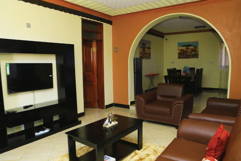 a living room with a tv and a couch and a table at Artistic Oasis 2Bedrm Apartment in Buwate