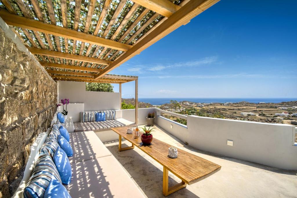 uma varanda com uma mesa de madeira e almofadas azuis em Overview Mykonos Apartments em Míconos