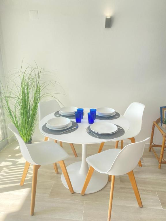 una mesa blanca con sillas blancas y una mesa con platos y gafas azules en NUEVO !!! Apartamento Peñíscola Playa con piscinas y tenis, en Peñíscola