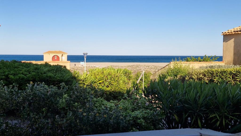 une vue d'une plage avec un bâtiment et l'océan dans l'établissement Maisonnette Port Leucate vue sur mer, à Port-Leucate
