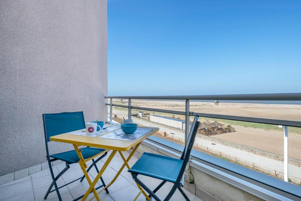 a table and two chairs on a balcony with a view of the beach at Face Mer - Bel appartement pour 4 in Saint-Brevin-les-Pins