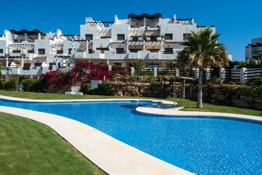 basen przed dużym białym budynkiem w obiekcie Luxurious and spacious apartment with a private garden and solarium with great views in Estepona área Marbella La Resina Country Golf w mieście Estepona