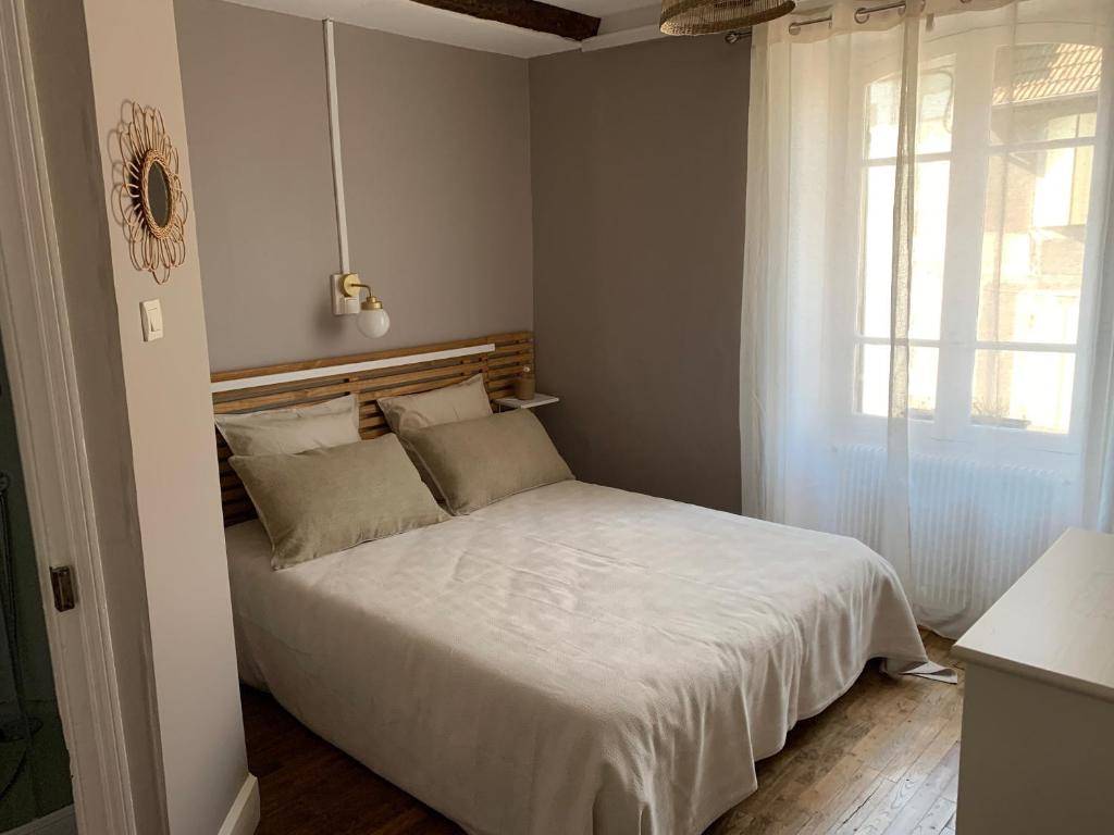 ein Schlafzimmer mit einem weißen Bett und einem Fenster in der Unterkunft L&#39;Authentique maison de charme in Aubusson