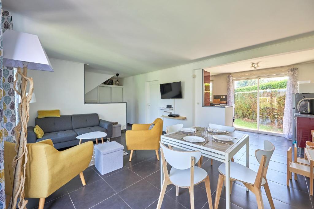 cocina y sala de estar con mesa y sillas en Les Roséales - Maison proche plage pour 6 voyageurs, en Courseulles-sur-Mer