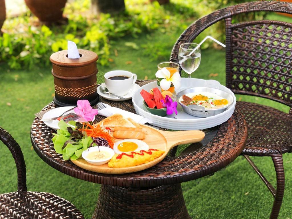 a table with a plate of breakfast food on it at Winner Serviced Apartment in Si Maha Phot