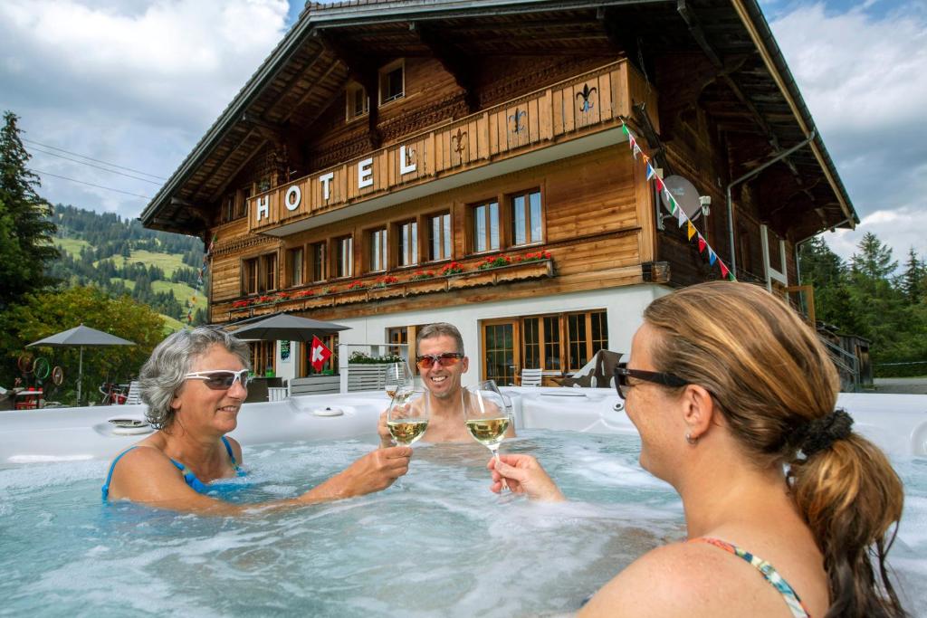 eine Gruppe von Personen in einem Whirlpool mit Gläsern Wein in der Unterkunft Le Petit Relais in Gstaad