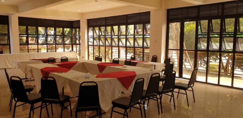 Habitación grande con mesas, sillas y ventanas. en Sky Beach Hotel, en Wakiso