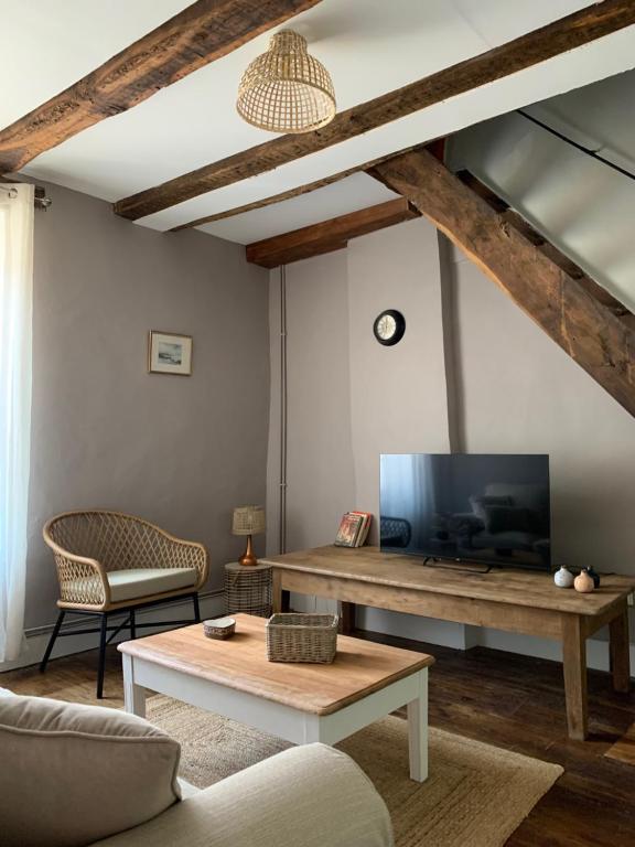 ein Wohnzimmer mit einem TV und einem Tisch in der Unterkunft L&#39;Authentique maison de charme in Aubusson