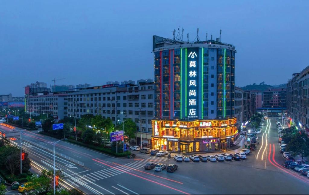 een stadsstraat met een hoog gebouw met lichten bij Morninginn, Zhenyu Plaza in Shaoyang County