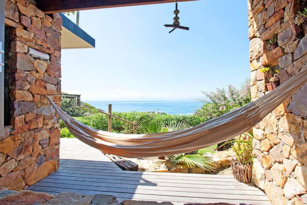 a hammock hanging outside of a house with the ocean at Vitamin-Sea in Cape Town