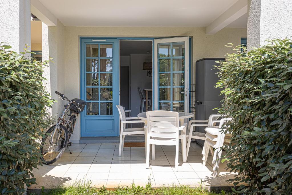 patio ze stołem i krzesłami oraz niebieskimi drzwiami w obiekcie Appartement Olivia w mieście Moliets-et-Maa