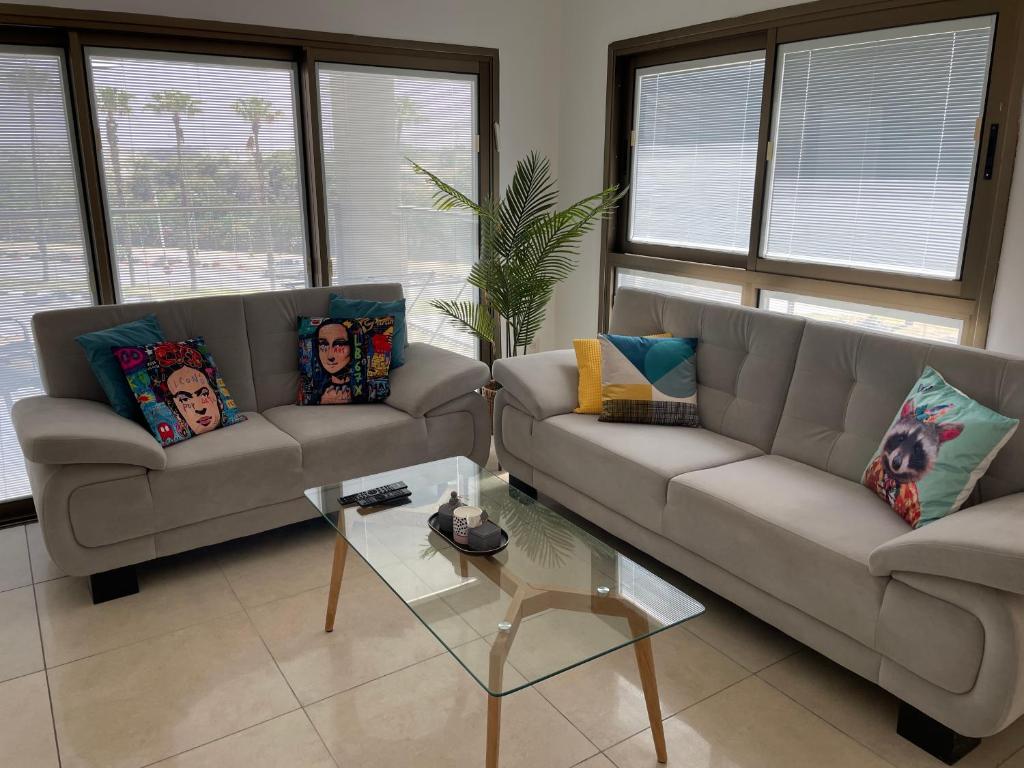 ein Wohnzimmer mit 2 Sofas und einem Tisch in der Unterkunft Unique beach apartment in Rischon LeZion