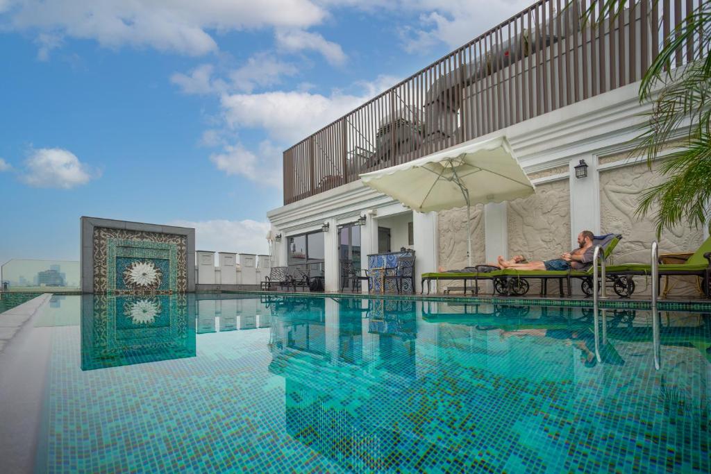 una persona sentada en una silla junto a una piscina en The Lapis Hotel en Hanói