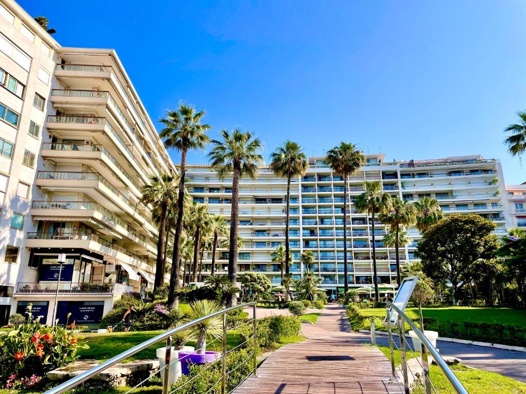 un grand immeuble avec des palmiers et une passerelle dans l'établissement Agence des Résidences - Appartements privés du 45 CROISETTE- Prestige, à Cannes