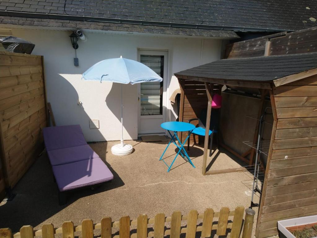 un patio avec une table, un parasol et des chaises dans l'établissement Studio Chez Coco, à Fouesnant