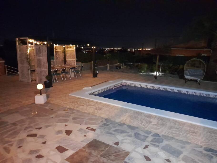 una piscina por la noche con mesa y sillas en Casa La Vista, en Albatera
