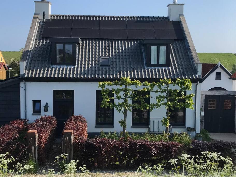 韦默尔丁厄aan de kust - PUUR POLDER HUIS - VP067的一栋带有黑色屋顶的白色房子