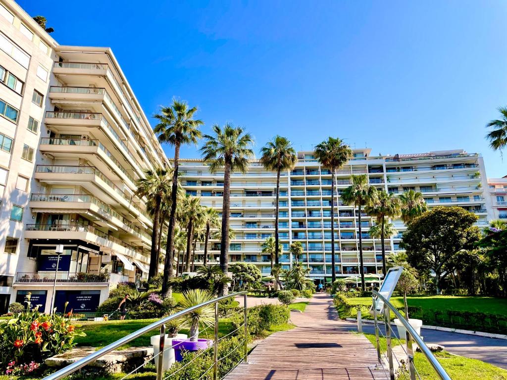 un grand immeuble avec des palmiers et une passerelle dans l'établissement Agence des Résidences - Appartements privés du 45 CROISETTE - Superieur, à Cannes