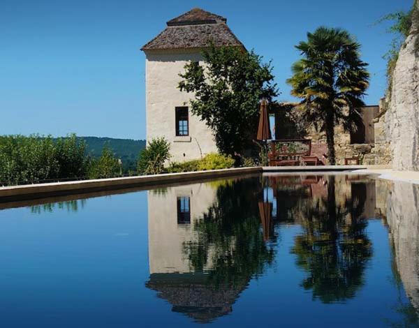 una casa con su reflejo en una piscina de agua en Sarrasins Bed and Breakfast, en Beynac-et-Cazenac