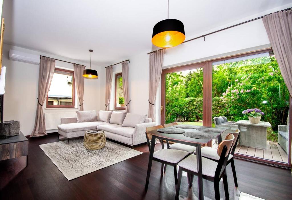 a living room with a couch and a table and chairs at InPoint 2-bedrooms Apartment with private garden and free parking in Krakow