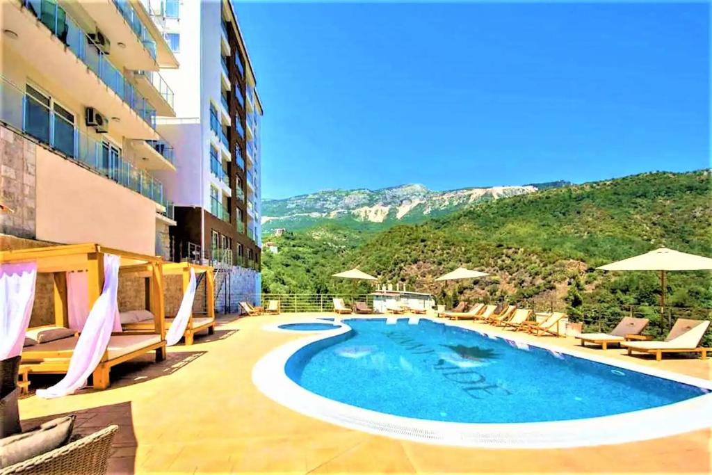 a hotel with a pool and chairs and a mountain at Sunny Side apartment in Bečići