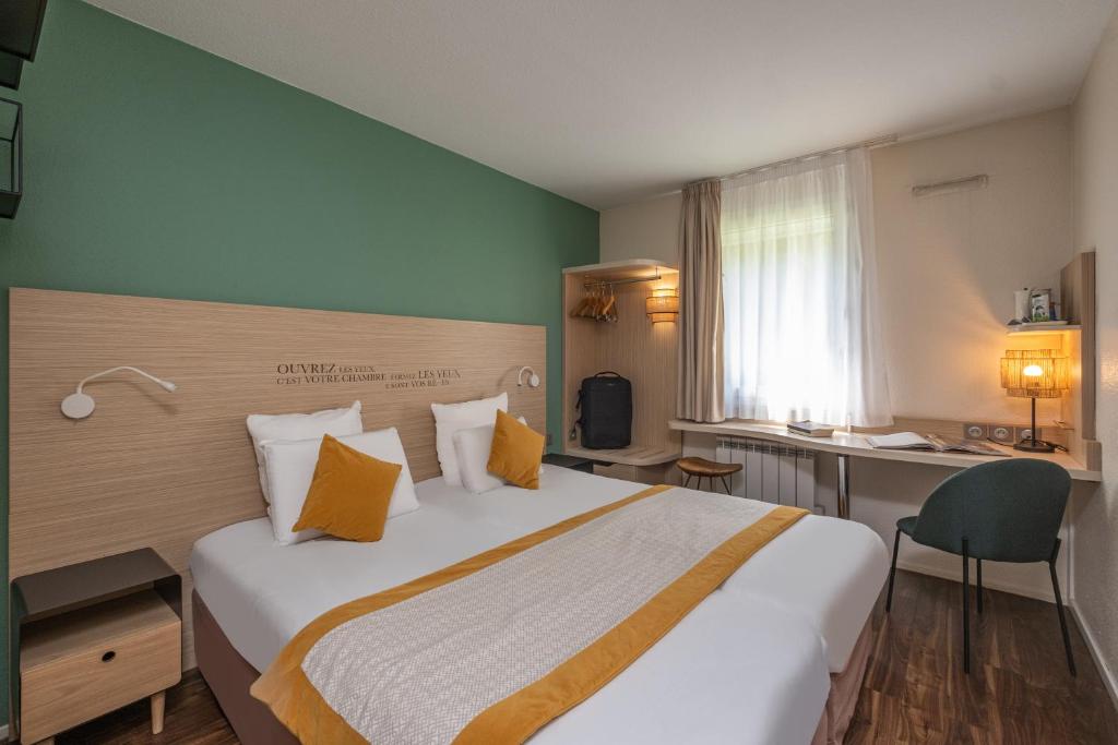 um quarto de hotel com uma cama grande e uma secretária em Kyriad Lyon Est - Bron Eurexpo Le Cottage em Bron
