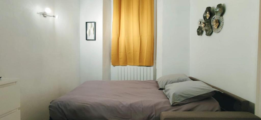 a bed in a bedroom with a yellow curtain at Le Cocon de Sisteron in Sisteron