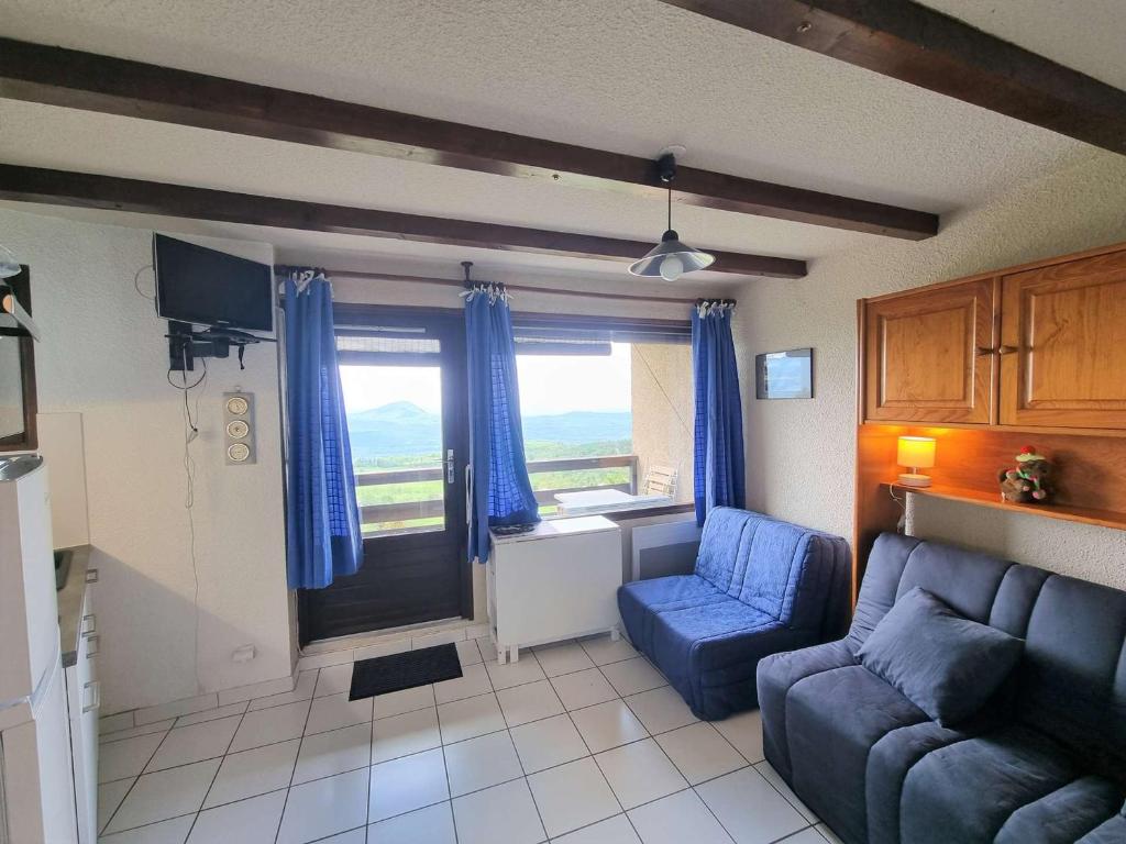 a living room with a blue couch and a window at Studio Saint-Michel-de-Chaillol, 1 pièce, 2 personnes - FR-1-393-80 in Saint-Michel-de-Chaillol