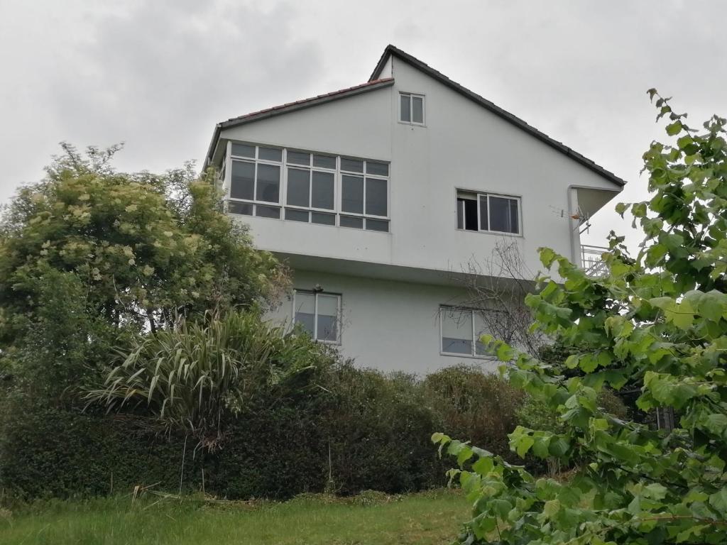 una casa blanca con ventanas en una colina en A CASA DOS AVÓS, en Celanova