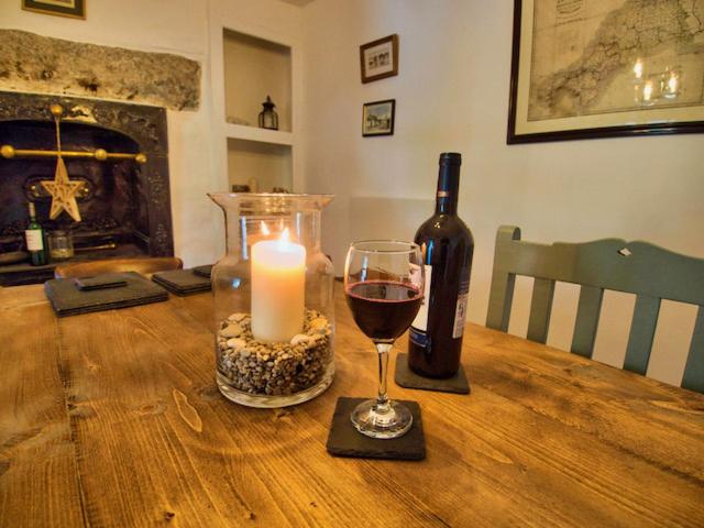 a candle and a bottle of wine on a wooden table at Knocker Cottage is a 3 bedroom made up of 1 double bedroom and 2 small double bedrooms in small village 10 min to beaches in Camborne