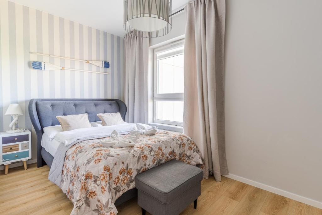- une chambre avec un lit doté d'une tête de lit bleue et d'une fenêtre dans l'établissement Hallera by Loft Apartments, à Gdańsk