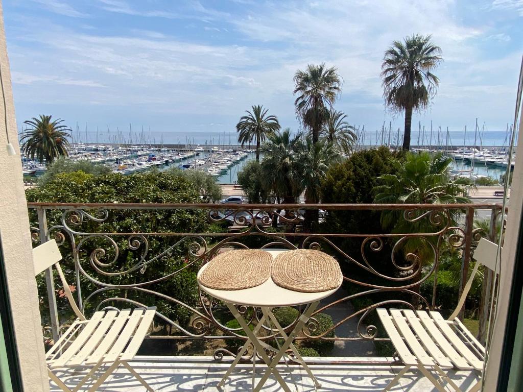 d'une table et de chaises sur un balcon avec des palmiers. dans l'établissement La Porte de France by Connexion, à Menton