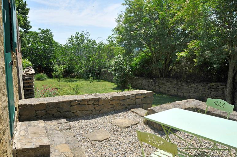 eine Steinmauer und einen Tisch im Hof in der Unterkunft Grange rénovée in La Serpent