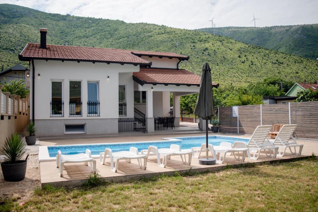 een villa met een zwembad en stoelen en een huis bij Villa Porto in Mostar