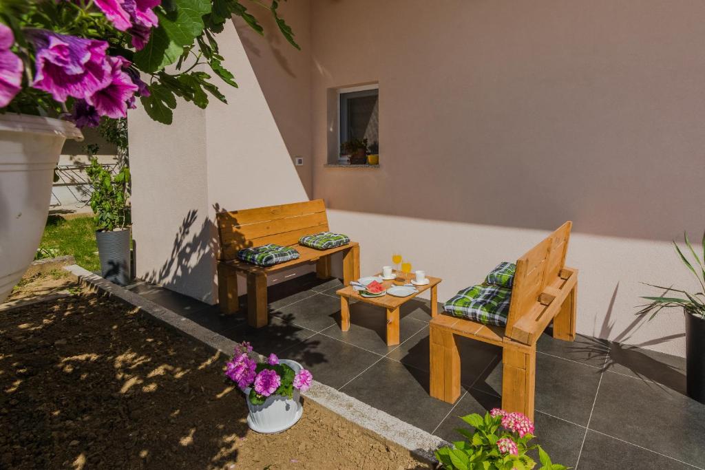 eine Terrasse mit 2 Stühlen, einem Tisch und Blumen in der Unterkunft Lovely apartment M&K in peaceful area - Zadar in Zadar