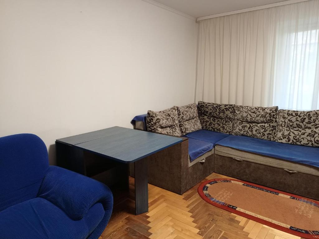 ein Wohnzimmer mit einem blauen Sofa und einem Tisch in der Unterkunft Трьохкімнатна квартира неподалік центру in Ternopil