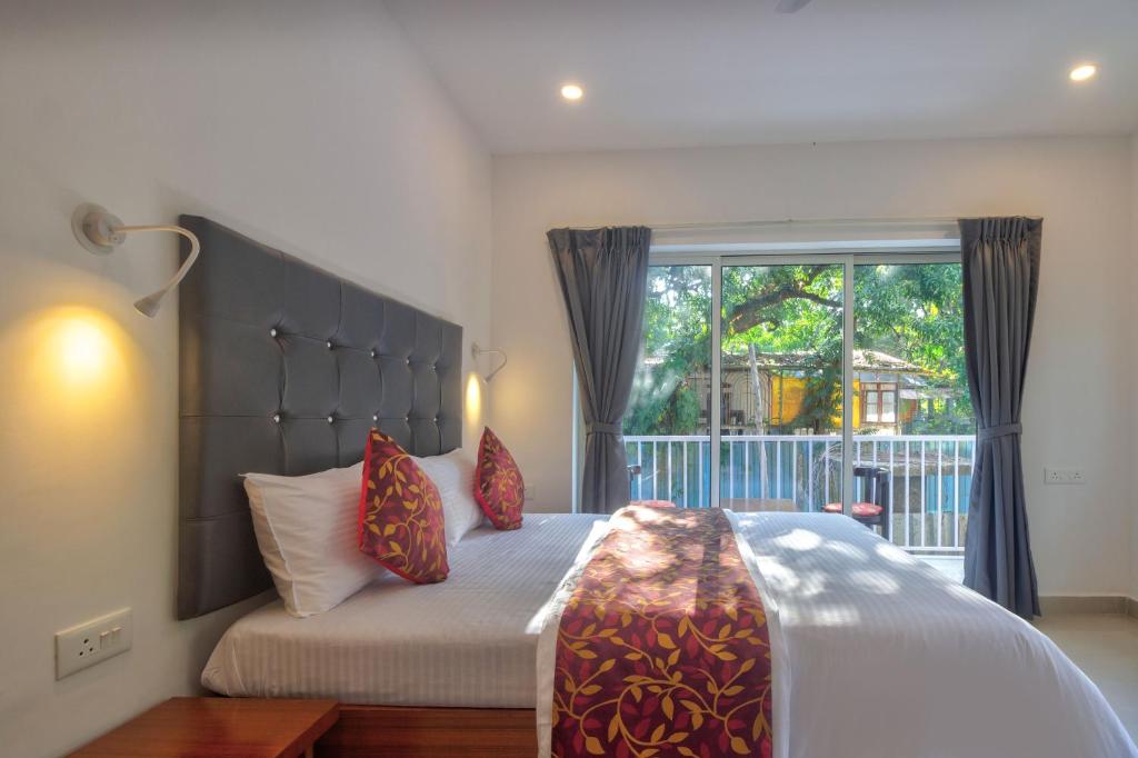 バガにあるAmazing 2BHK Apartment Near Baga Beachの大きな窓のあるベッドのある寝室