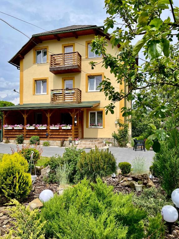 a yellow house with a garden in front of it at Ніч над Карпатами in Slavske