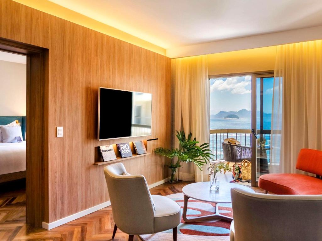 a hotel room with a bed and a television and a table at Fairmont Rio de Janeiro Copacabana in Rio de Janeiro