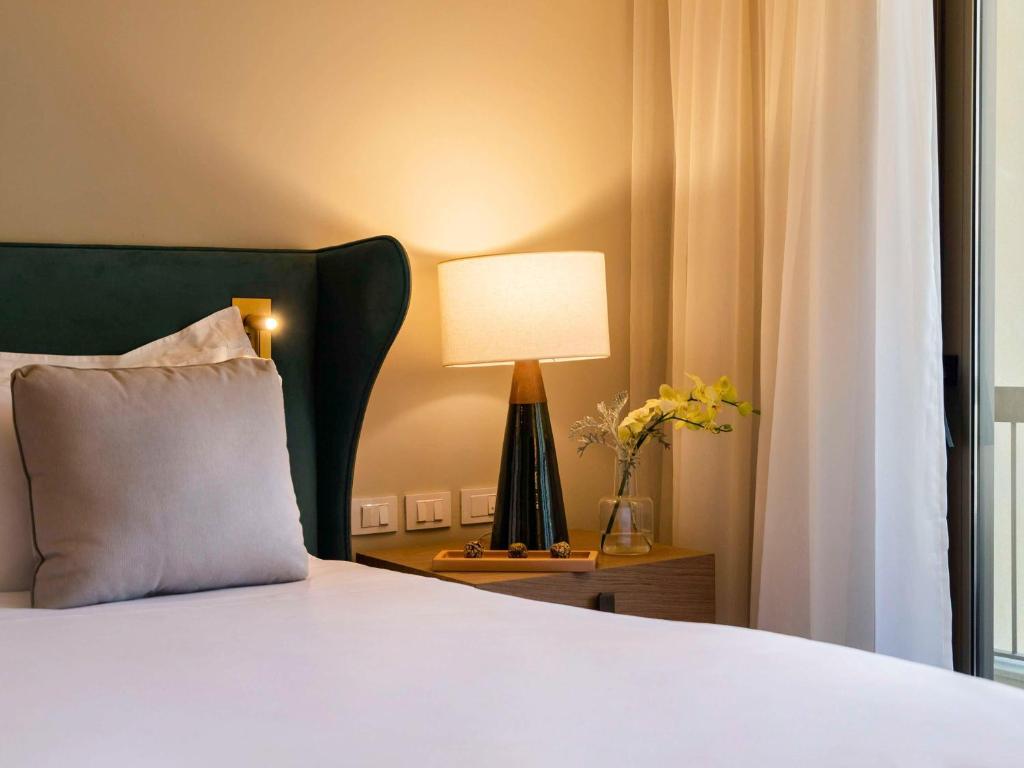 a bedroom with a bed with a green headboard and a lamp at Fairmont Rio de Janeiro Copacabana in Rio de Janeiro