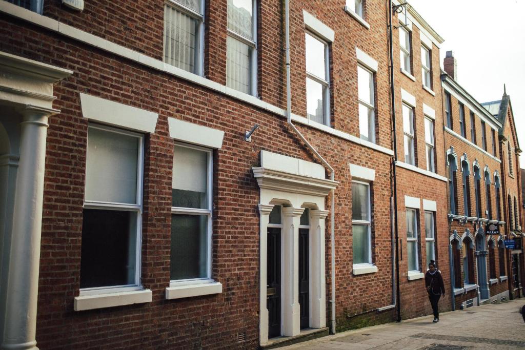 a man walking down a street next to a brick building at 7 Cannon Street in Preston