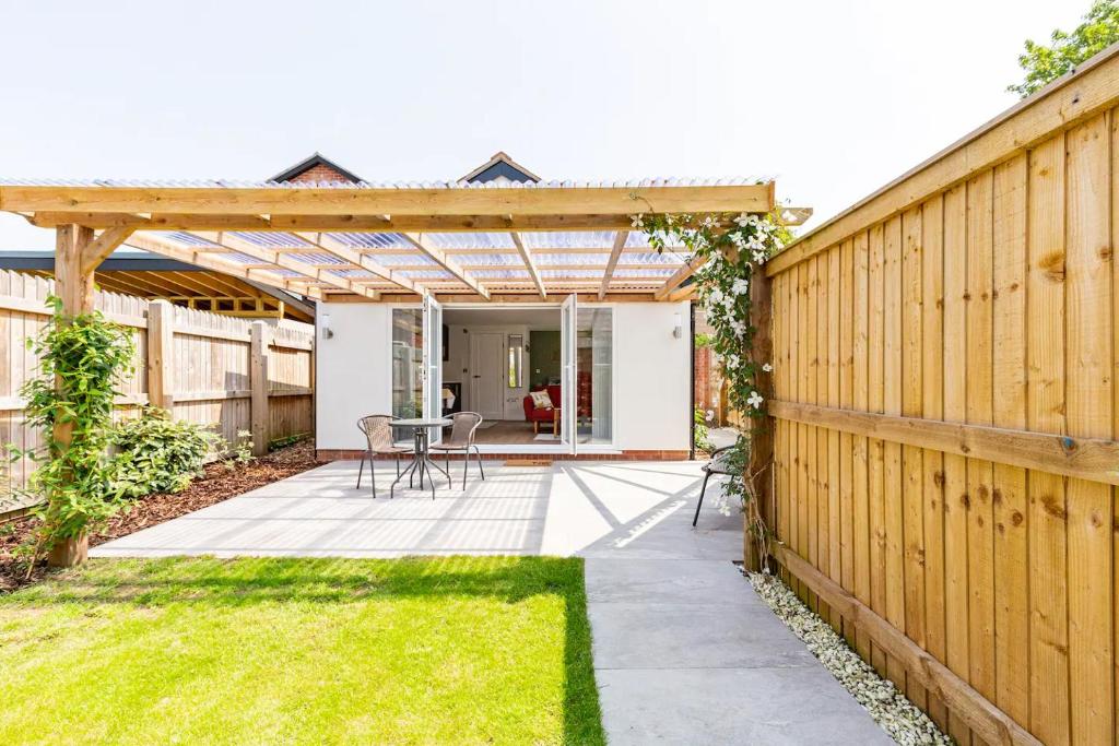 a backyard with a wooden pergola and grass at Charming Chester Studio with private garden & free parking in Chester