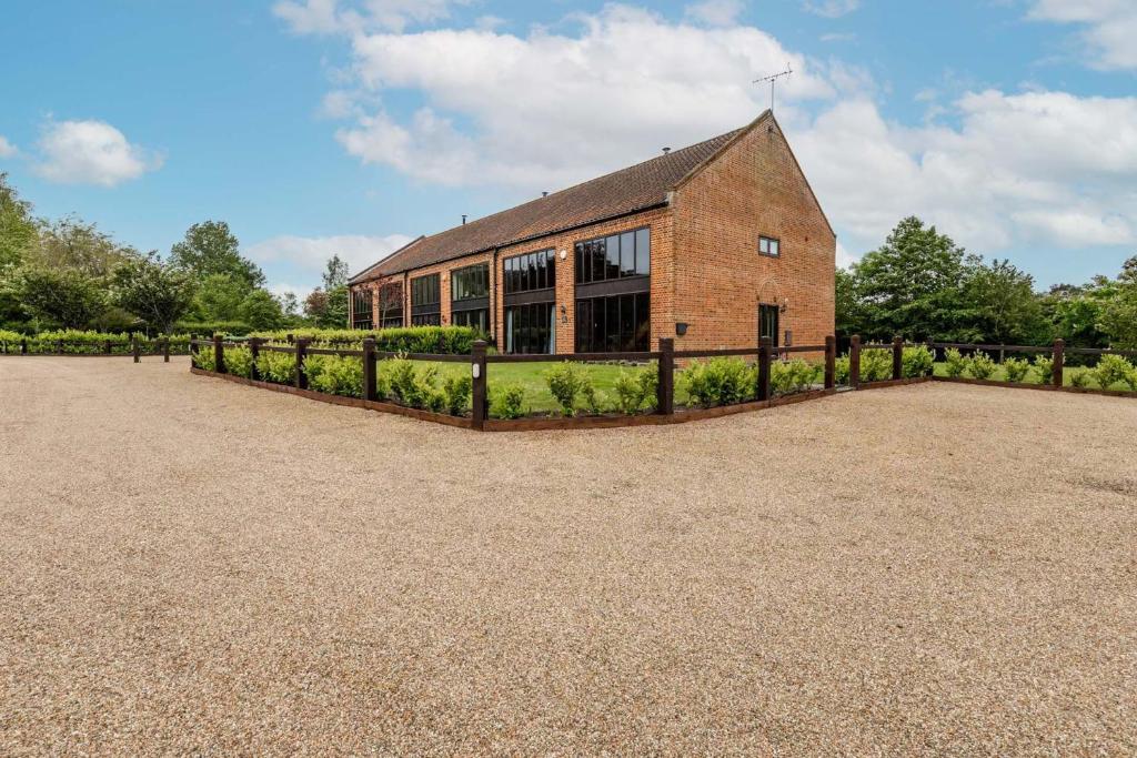 un edificio de ladrillo con una valla delante en Owl Barn, en Sculthorpe