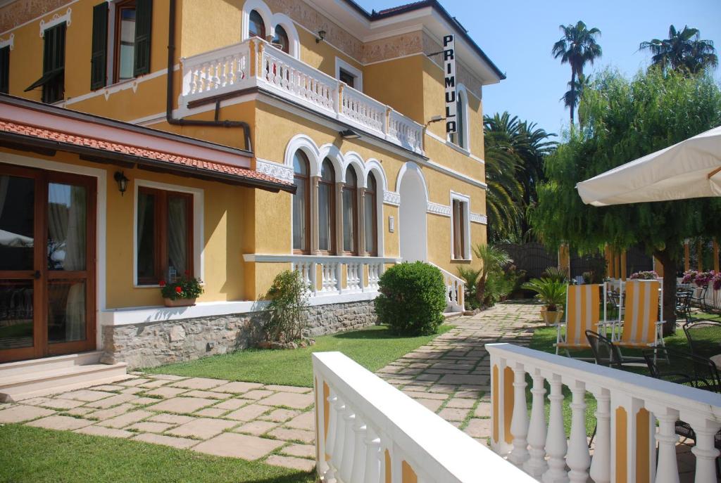 una casa amarilla con una cerca blanca delante de ella en Hotel Primula, en Alassio