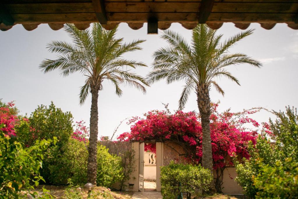 a house with palm trees and pink flowers at Baccu Mandara Sea View Modern Villa with Parking! in Geremeas