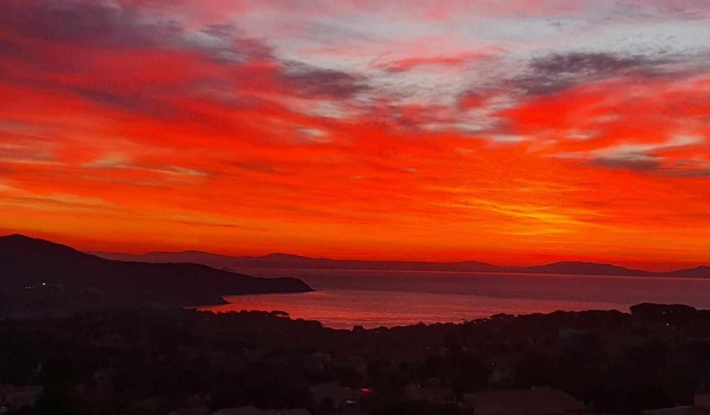 a sunset over a body of water with a red sky at Appartamento Blu Relax in Capoliveri